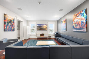 Modern waiting room with gray modular sofas, white walls, and colorful wall art.