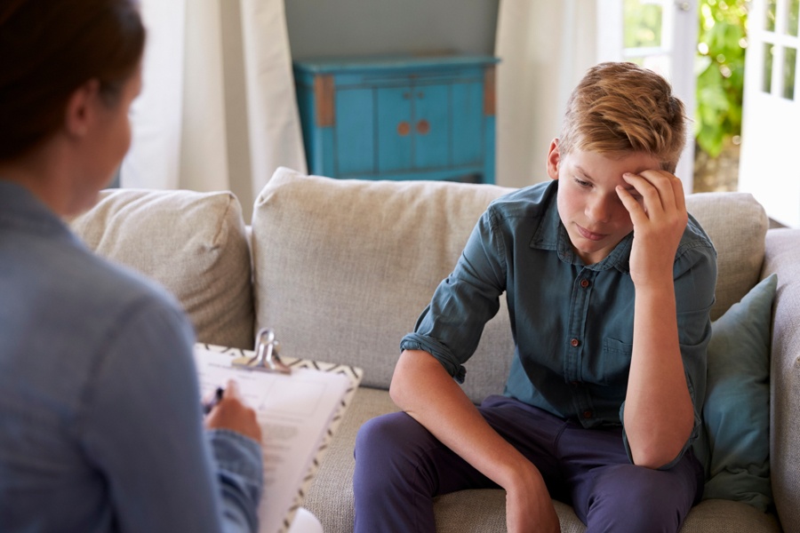 a teen with hand on head in therapy