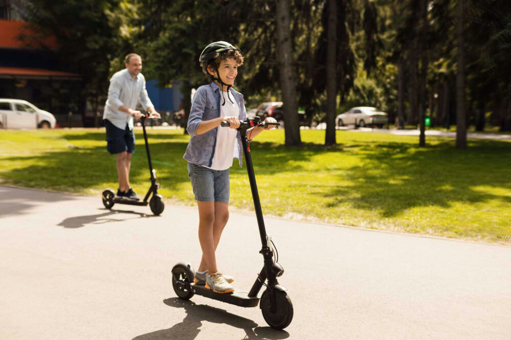 teen riding a scouter with dad for summer activity